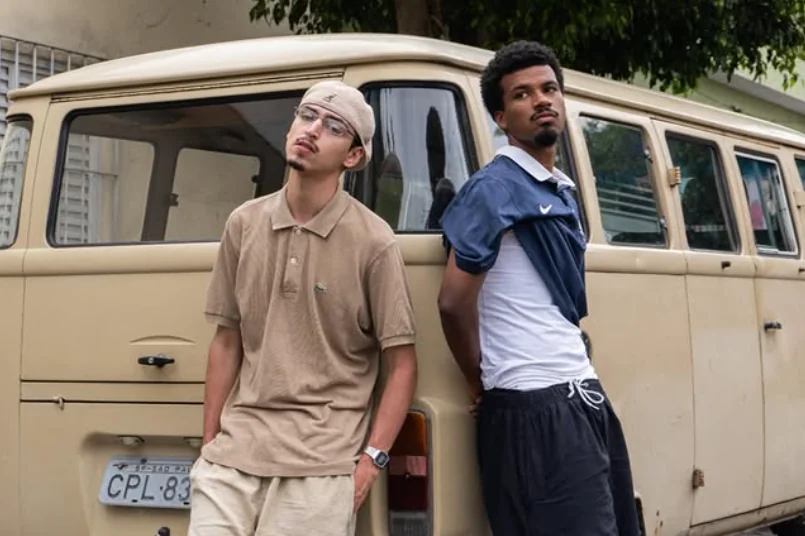 Dois integrantes da Milênio encostados numa Kombi, na rua.